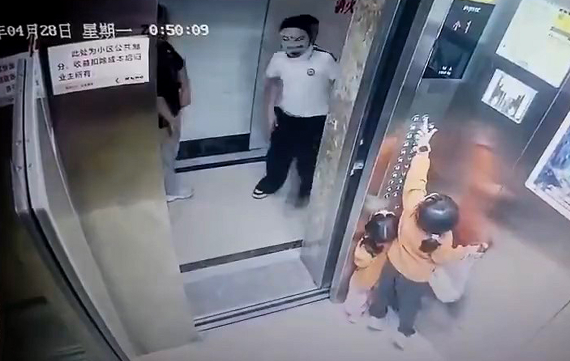 Masked woman scares two girls in elevator in Xinluo District, China, April 28, 2025. She prevented them from closing the elevator door. Note: Photo is a screenshot from a video. Masked woman scares two girls
