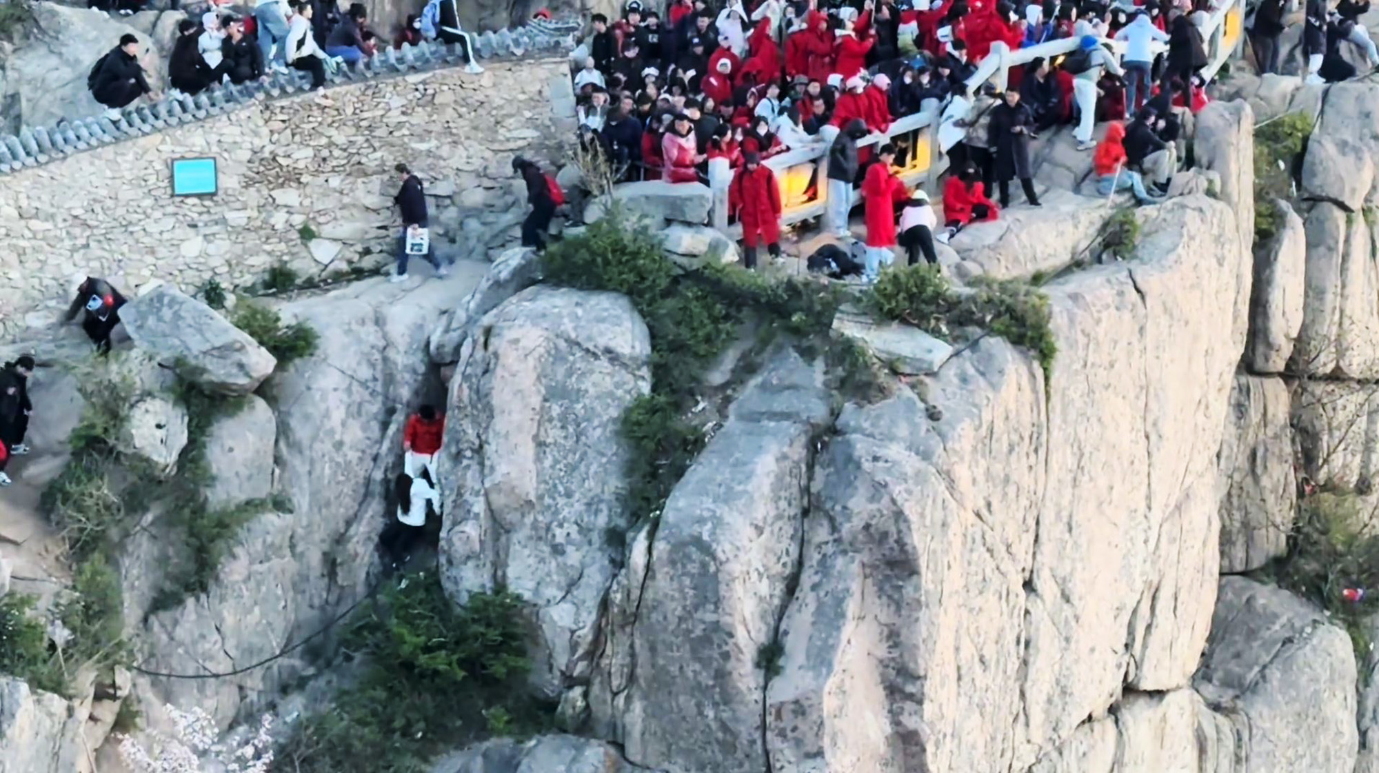 Two tourists fall while trying to climb over wall on Mount Tai in Shandong province, China. The footage emerged on 5 May, 2025. Note: Photo is a screenshot from a video Two tourists fall while trying to climb over wall