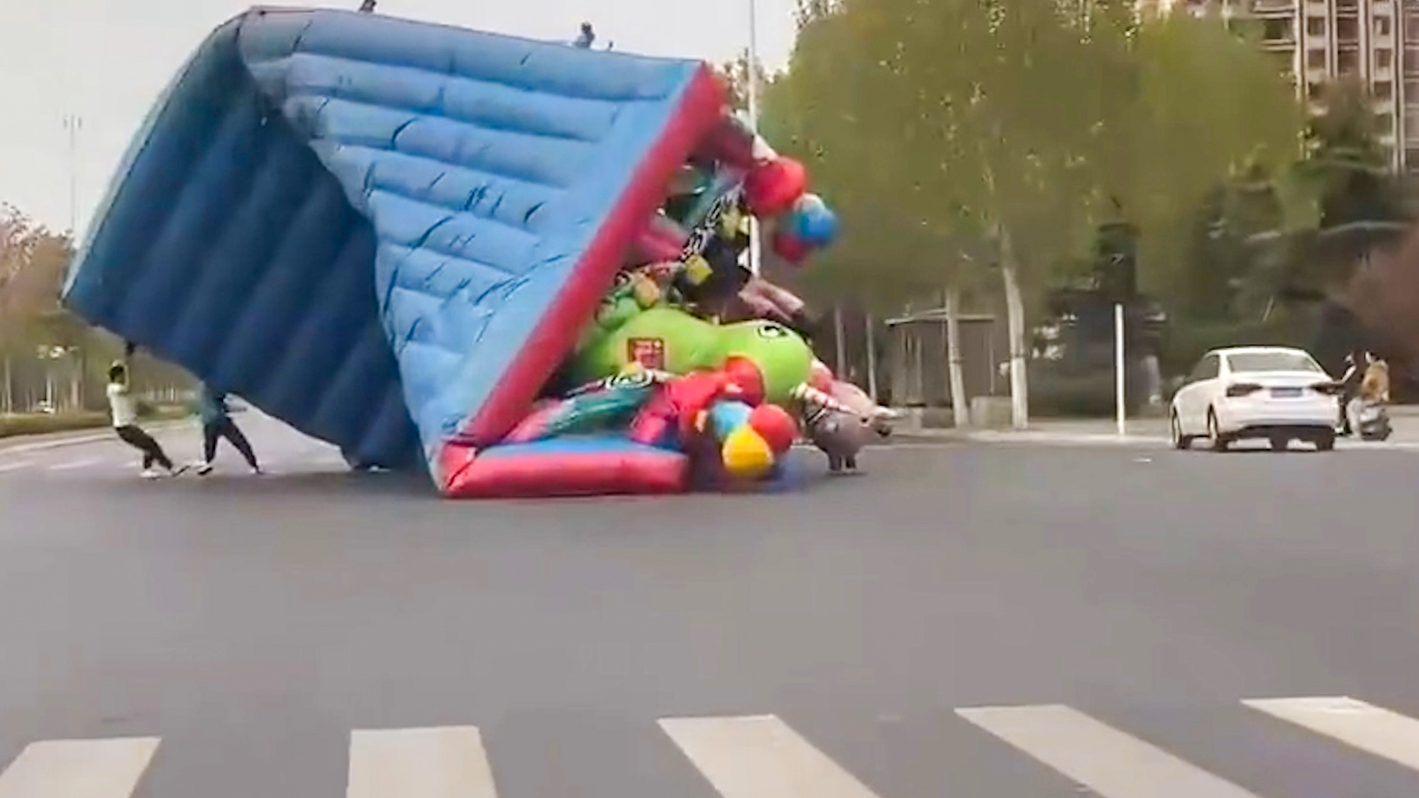 Video shows a man carrying a bouncy castle in Zhengzhou, Henan, China, on Apr.04, 2025. It was blown away from an amusement park. Video shows a man carrying a bouncy castle in Zhengzhou, Henan, China.